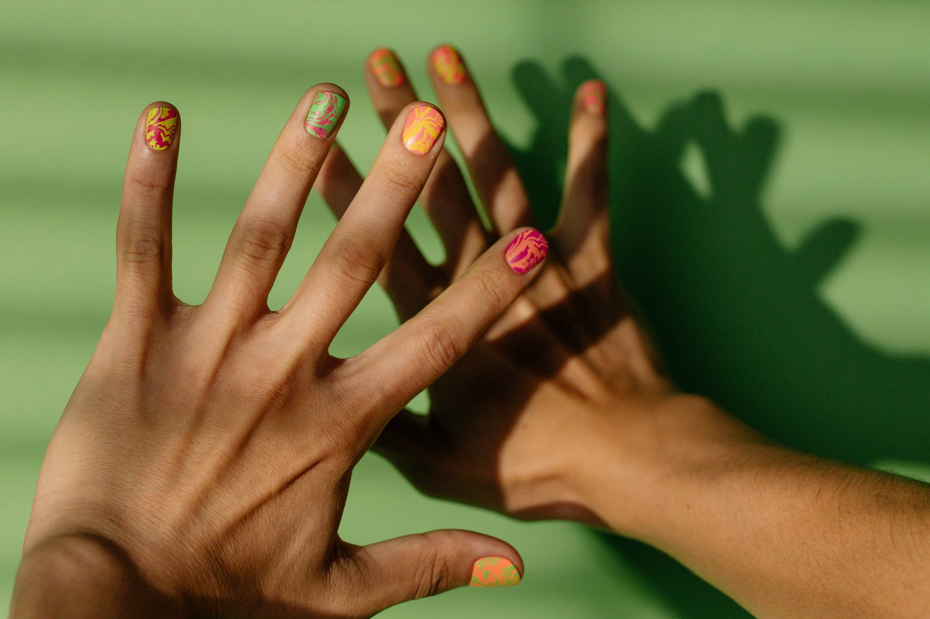 person with pink manicure on green surface